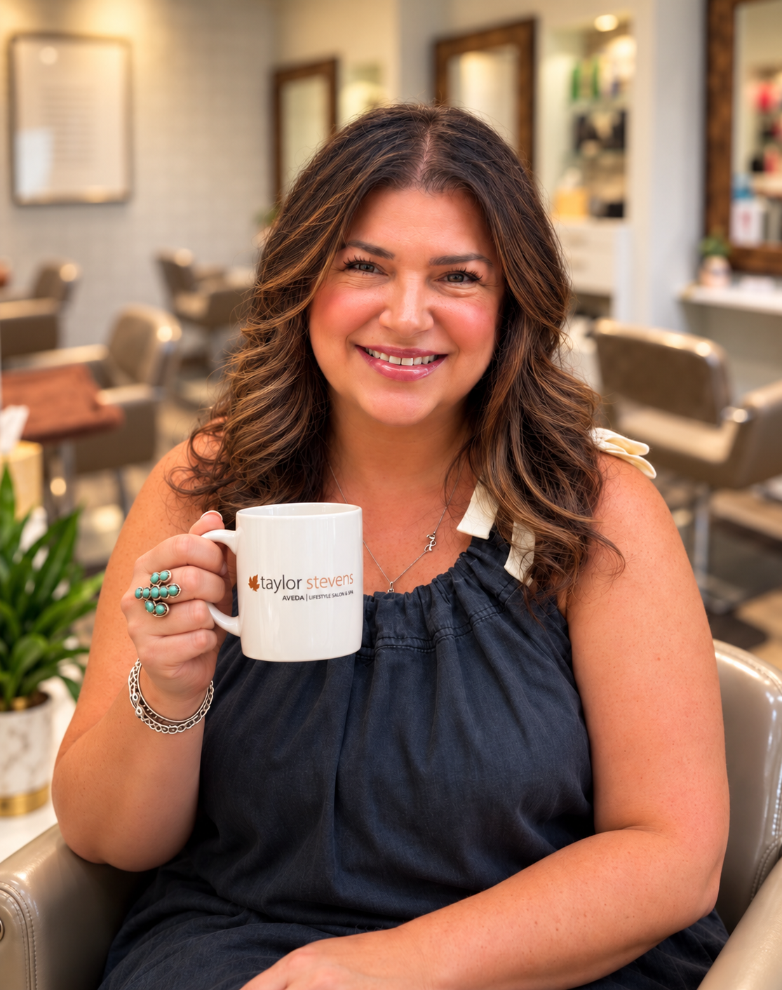 Andrea Swanson smiling with a Taylor Stevens mug in the salon